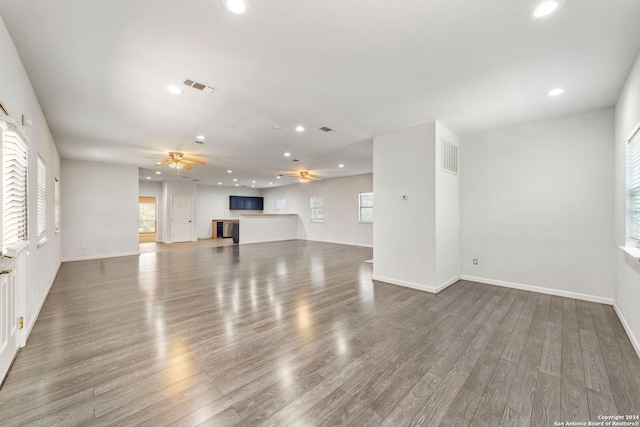 unfurnished living room featuring wood-type flooring, plenty of natural light, and ceiling fan