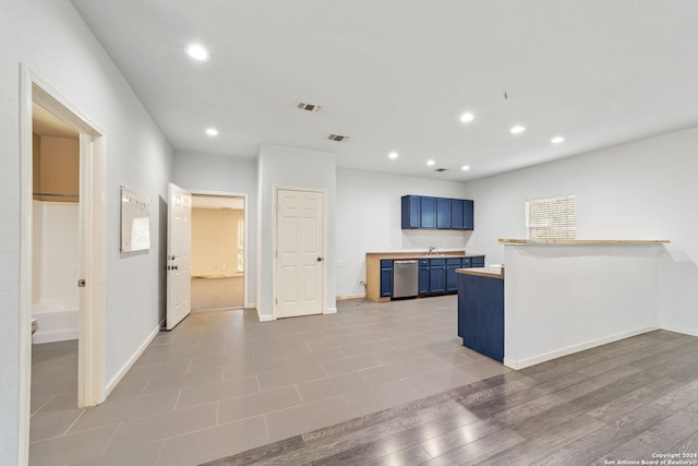 kitchen featuring blue cabinets, light hardwood / wood-style flooring, stainless steel dishwasher, and sink