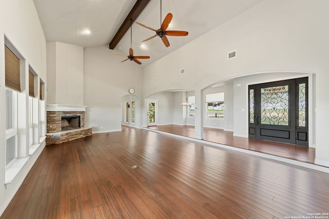 unfurnished living room featuring a fireplace, dark hardwood / wood-style flooring, high vaulted ceiling, beamed ceiling, and ceiling fan