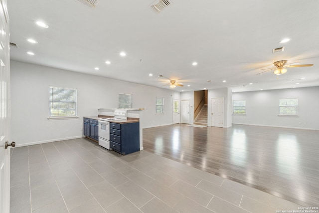 unfurnished living room with ceiling fan, a wealth of natural light, and light hardwood / wood-style floors