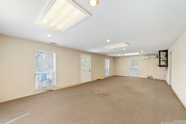 spare room with an AC wall unit and carpet flooring