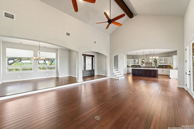 unfurnished living room featuring ceiling fan with notable chandelier, hardwood / wood-style floors, high vaulted ceiling, beamed ceiling, and sink