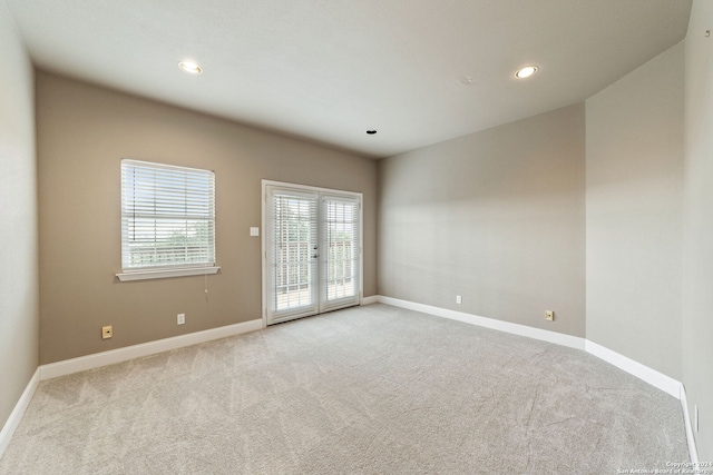 unfurnished room featuring french doors and light colored carpet