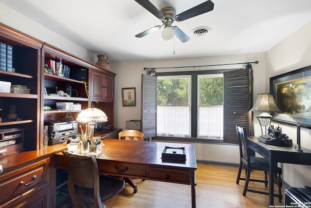 office with light wood-type flooring and ceiling fan