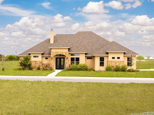 view of front facade with stucco siding, a front lawn, stone siding, french doors, and a chimney