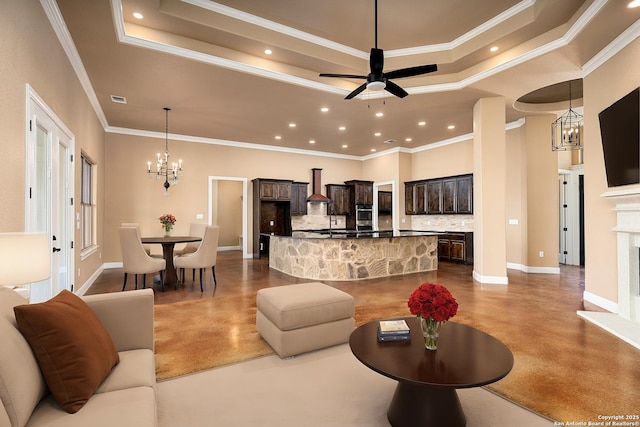 living room with a stone fireplace, ceiling fan with notable chandelier, concrete floors, ornamental molding, and a raised ceiling