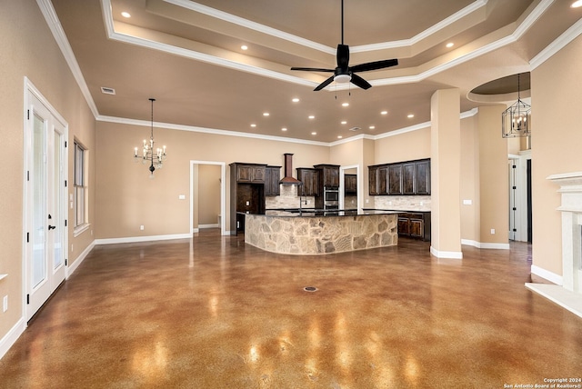 unfurnished living room with ceiling fan with notable chandelier, concrete flooring, ornamental molding, and a tray ceiling