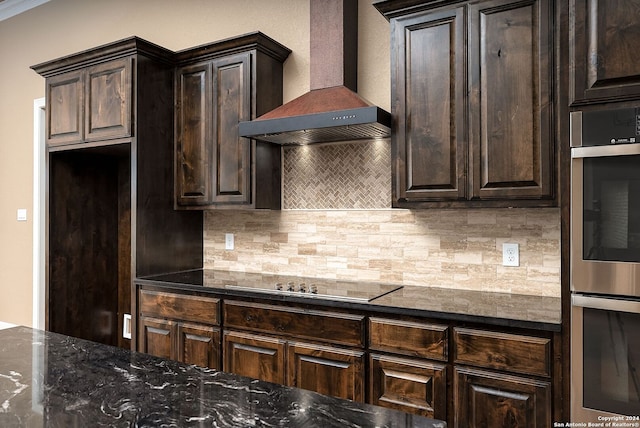 kitchen with wall chimney range hood, backsplash, dark brown cabinetry, black electric cooktop, and double oven