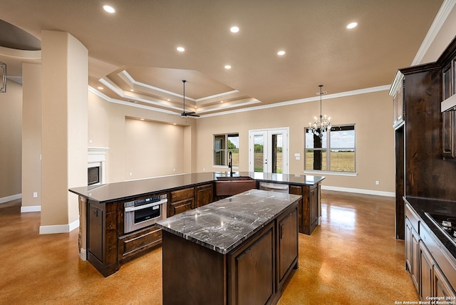 kitchen featuring appliances with stainless steel finishes, crown molding, a large island, and dark stone counters