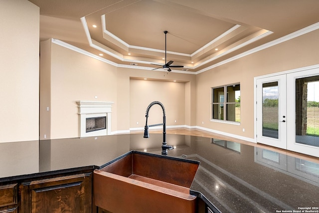 kitchen with ceiling fan, a raised ceiling, sink, and plenty of natural light