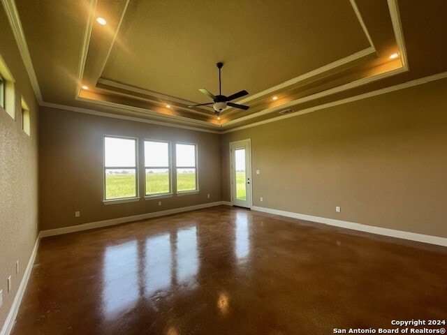 empty room with ceiling fan, a raised ceiling, and ornamental molding