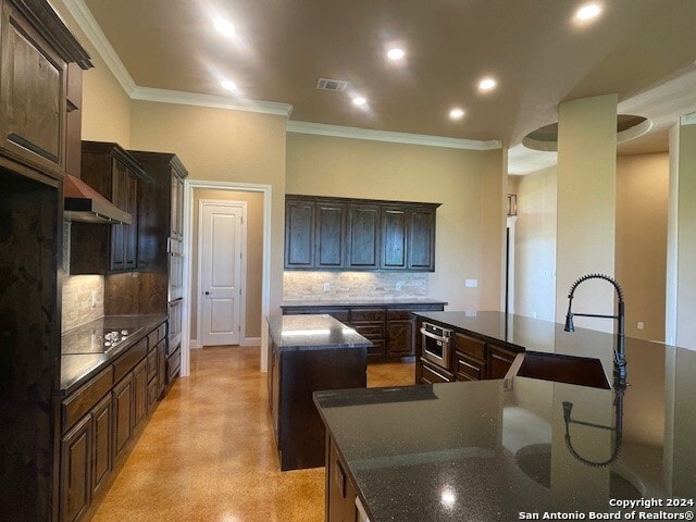 kitchen featuring sink, decorative backsplash, a center island, and dark brown cabinets