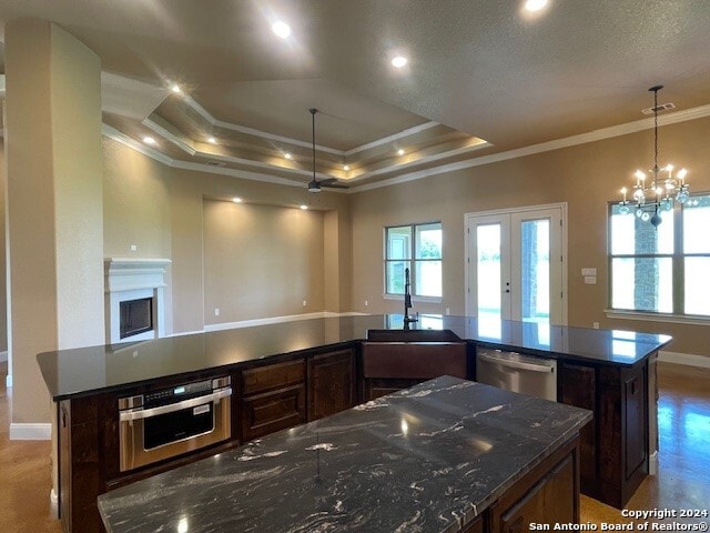 kitchen with appliances with stainless steel finishes, a tray ceiling, crown molding, and dark brown cabinets