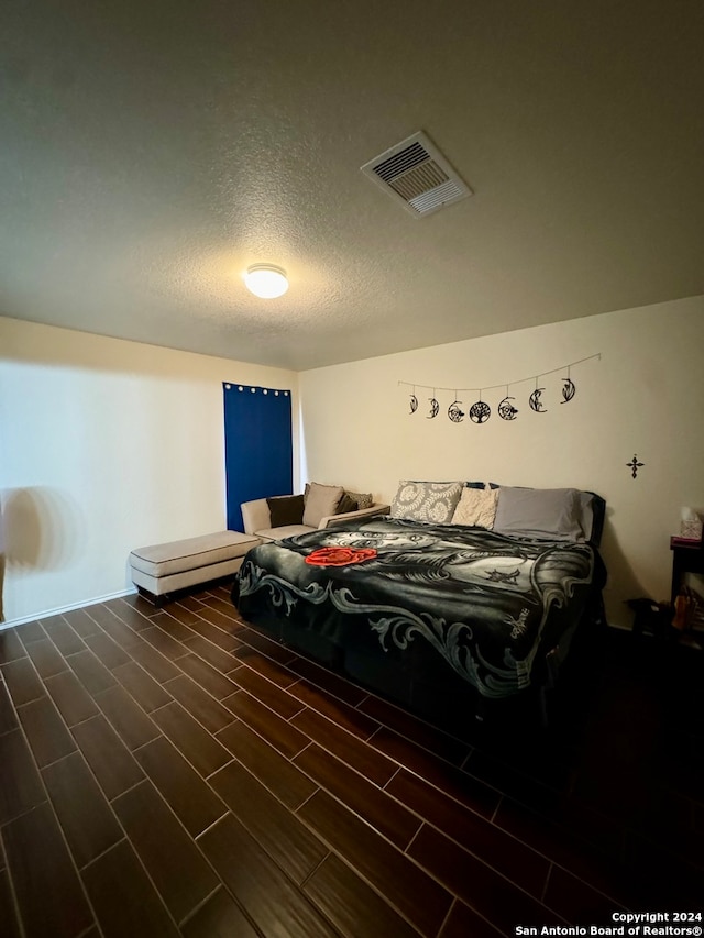 bedroom with a textured ceiling and dark hardwood / wood-style floors