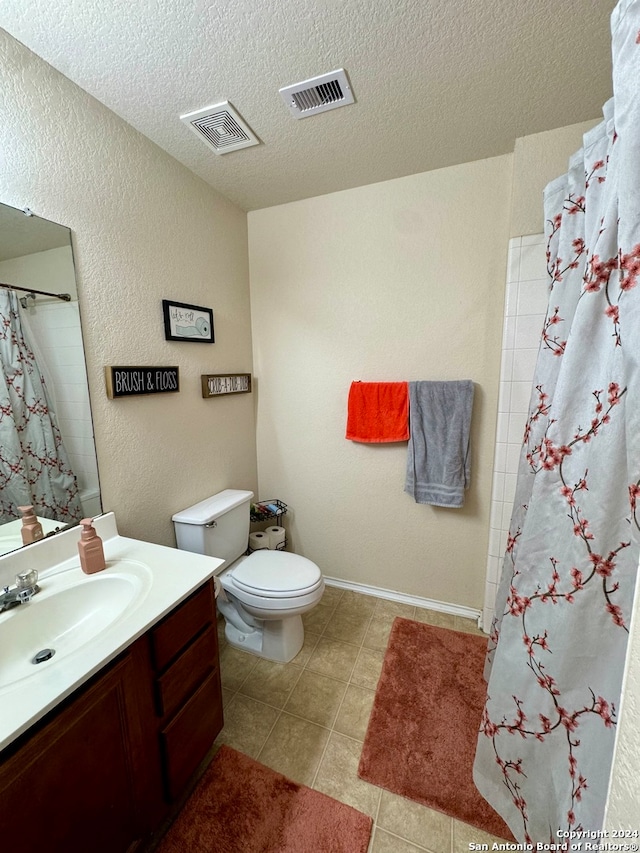 bathroom with tile patterned floors, a textured ceiling, vanity, and toilet