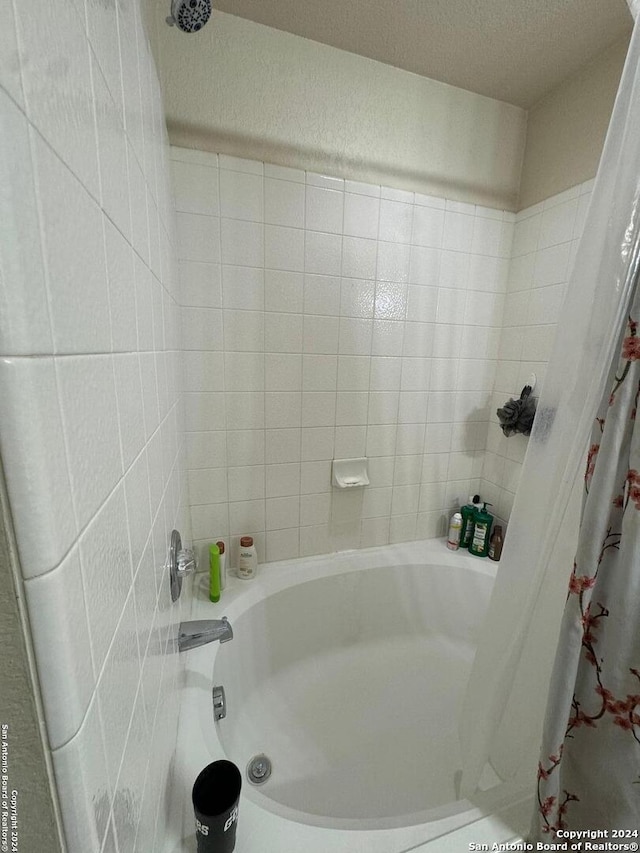 bathroom featuring a textured ceiling and shower / bath combination with curtain