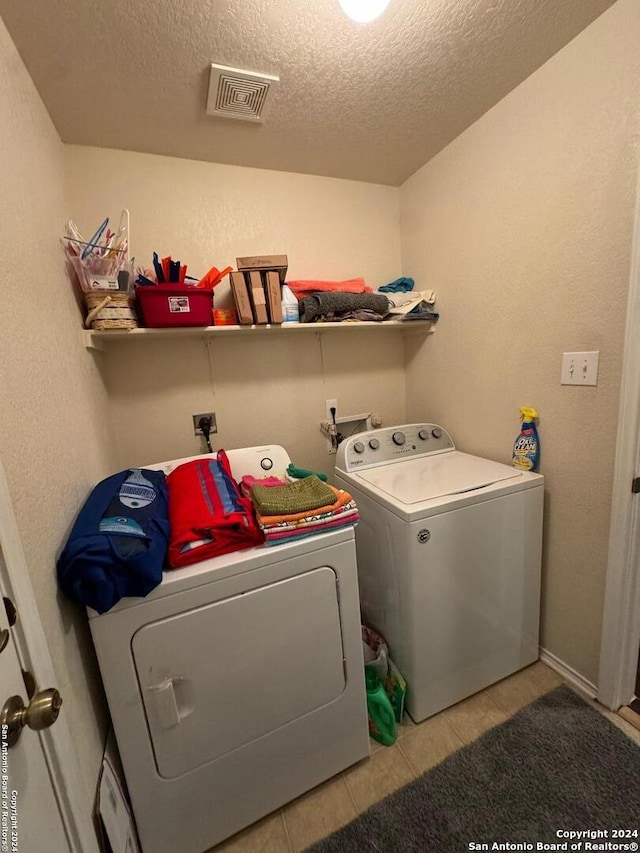 laundry area featuring a textured ceiling, light tile patterned floors, and washer and clothes dryer