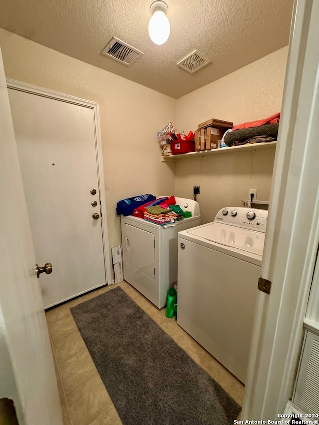 clothes washing area featuring a textured ceiling, light tile patterned floors, and independent washer and dryer