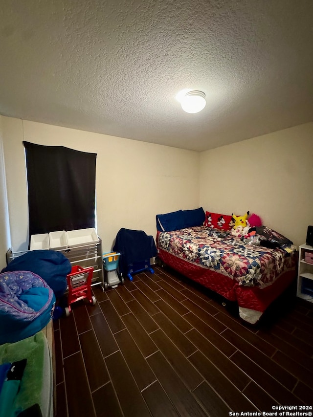 bedroom with a textured ceiling and dark wood-type flooring