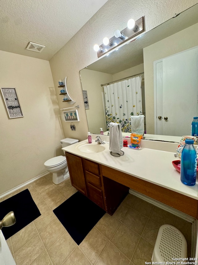 bathroom featuring a textured ceiling, toilet, vanity, and tile patterned flooring