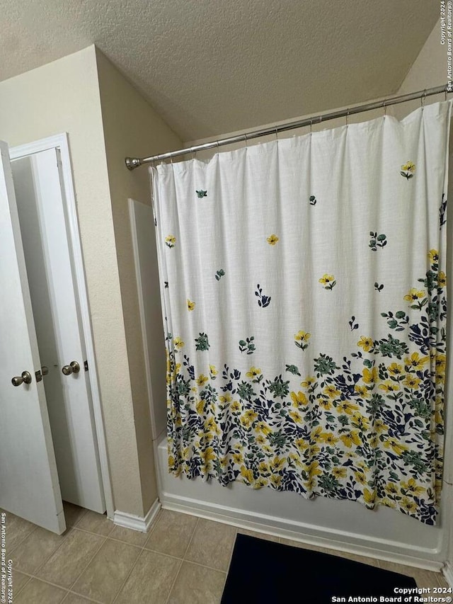 bathroom with a textured ceiling, shower / tub combo, and tile patterned floors