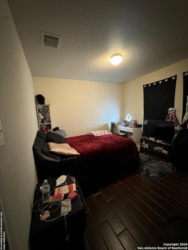 bedroom featuring dark hardwood / wood-style floors and a textured ceiling