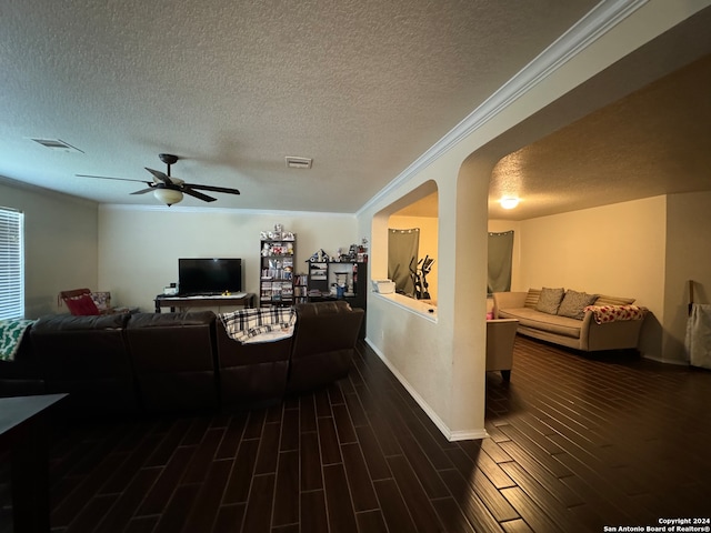 living room with a textured ceiling, crown molding, dark wood-type flooring, and ceiling fan