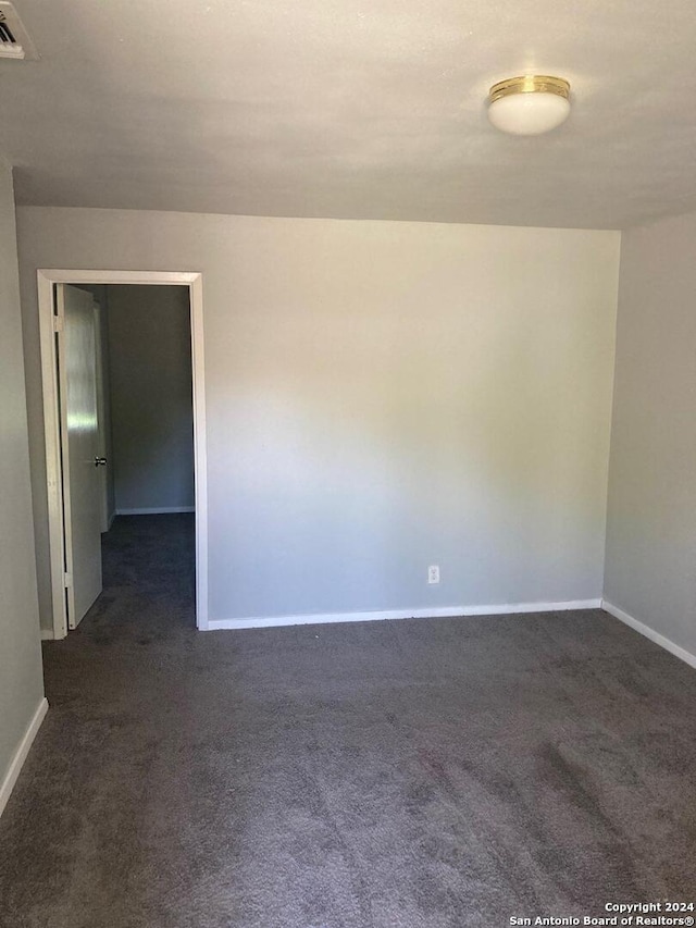 unfurnished room with visible vents, baseboards, and dark colored carpet