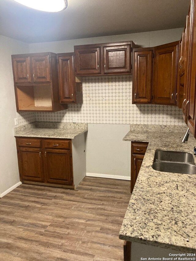 kitchen featuring a sink, decorative backsplash, baseboards, and dark wood finished floors