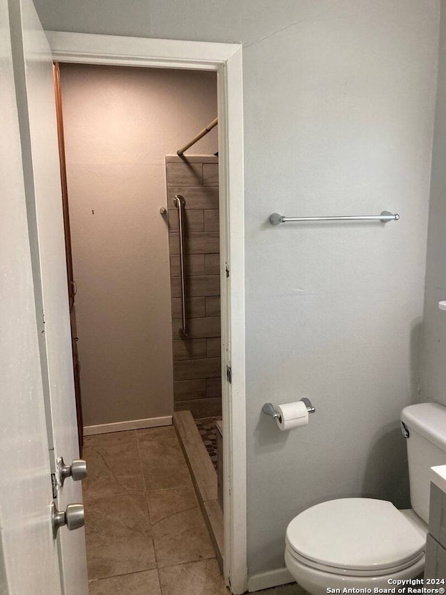 bathroom featuring a tile shower, tile patterned floors, toilet, and baseboards