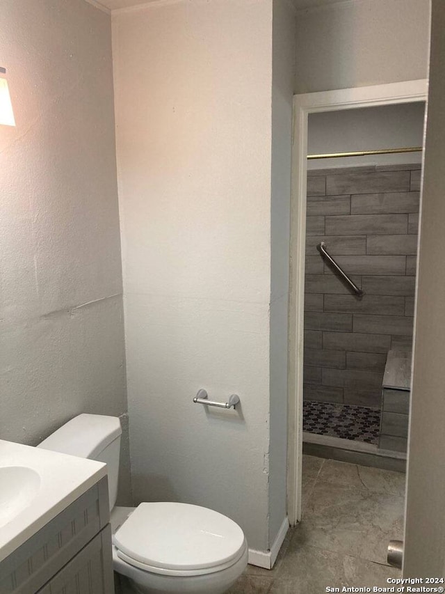 bathroom with tile patterned floors, a tile shower, vanity, and toilet