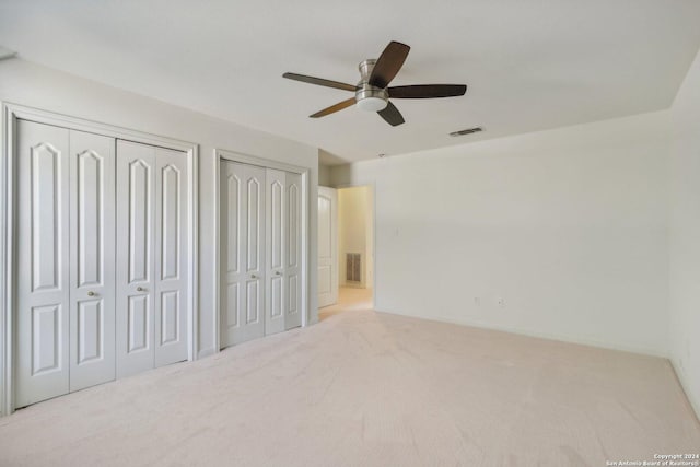 unfurnished bedroom with carpet floors, visible vents, and multiple closets
