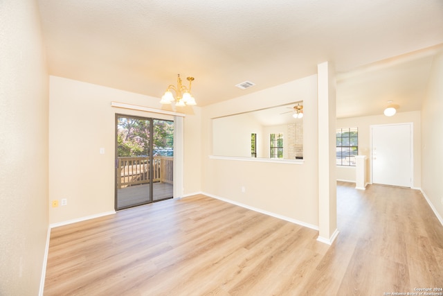 empty room featuring ceiling fan with notable chandelier, light hardwood / wood-style floors, and a textured ceiling