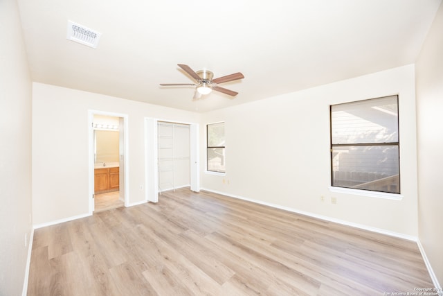 unfurnished bedroom featuring connected bathroom, light hardwood / wood-style floors, a closet, and ceiling fan