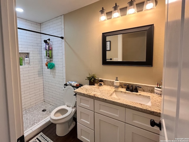 bathroom featuring tiled shower, wood-type flooring, vanity, and toilet