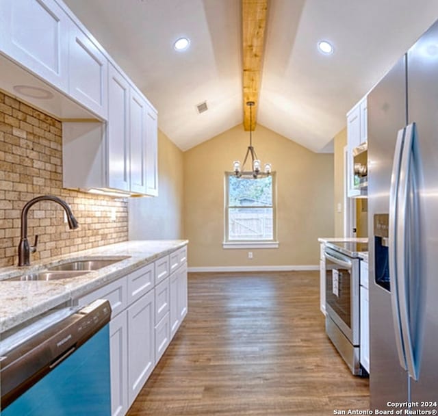 kitchen featuring light wood-type flooring, stainless steel appliances, white cabinetry, and decorative backsplash