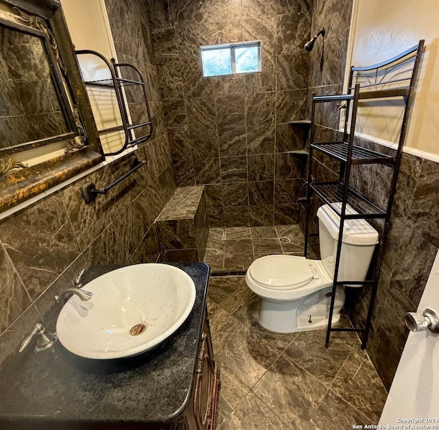 bathroom with tile walls, toilet, vanity, and tile patterned floors