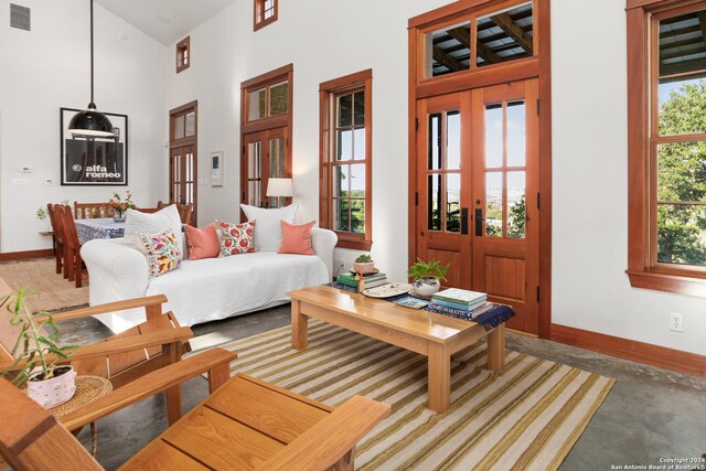 living room featuring french doors, concrete flooring, and a wealth of natural light