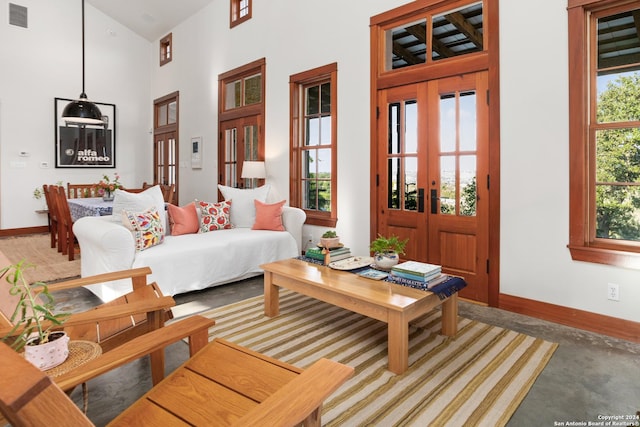 living area featuring french doors, a high ceiling, visible vents, and baseboards