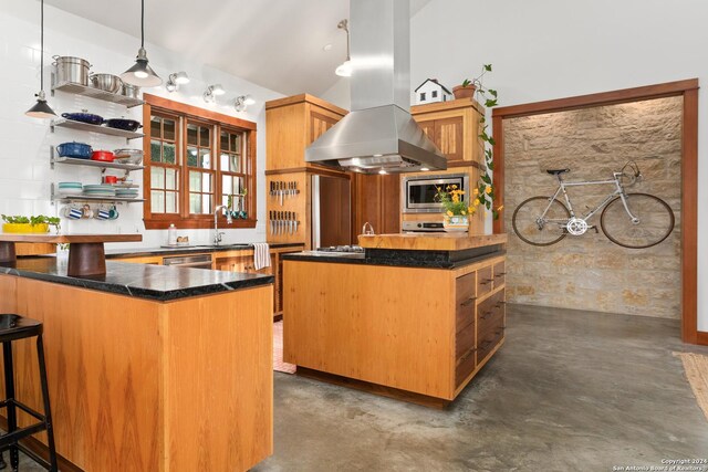 kitchen with lofted ceiling, pendant lighting, island range hood, stainless steel microwave, and a center island