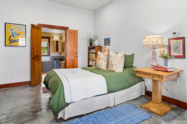 bedroom featuring concrete flooring, connected bathroom, and a high ceiling