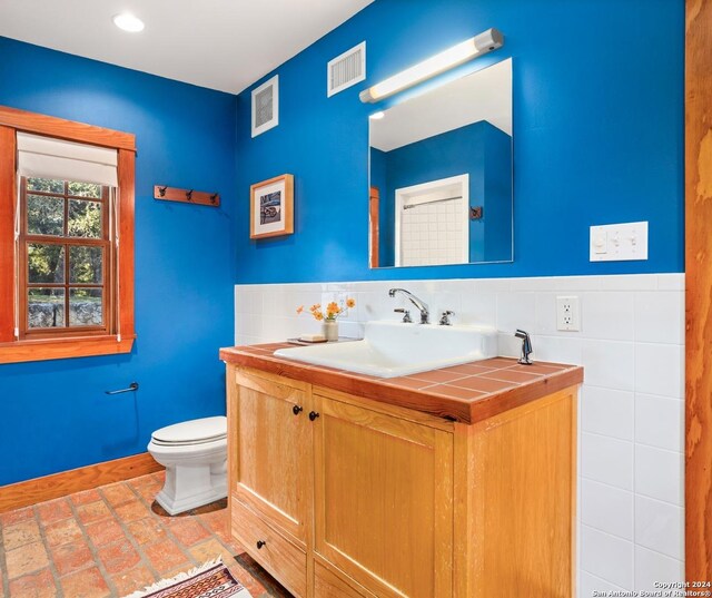 bathroom with vanity, decorative backsplash, and toilet