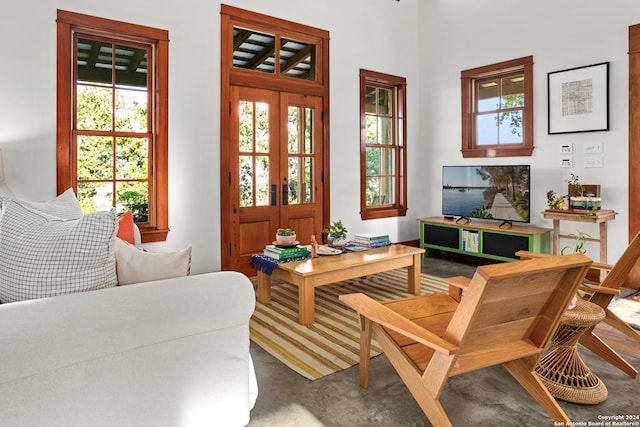 sitting room featuring concrete floors, french doors, and plenty of natural light