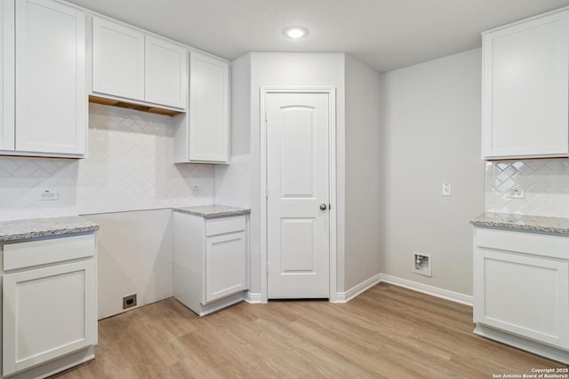 kitchen featuring backsplash, light stone counters, white cabinets, and light wood-type flooring