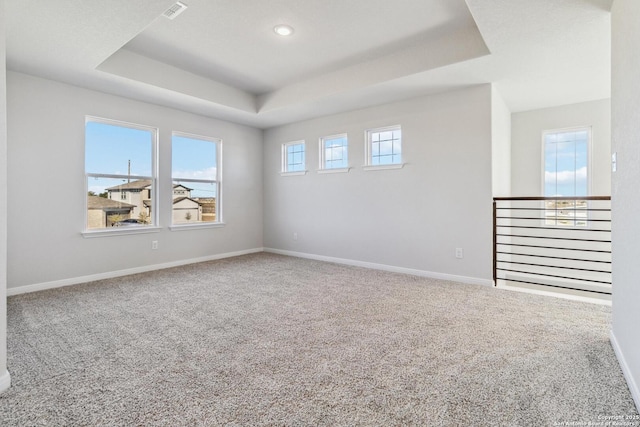 carpeted empty room with a tray ceiling