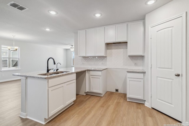 kitchen with kitchen peninsula, white cabinets, plenty of natural light, and sink