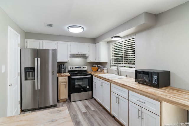 kitchen featuring stainless steel appliances, wooden counters, sink, white cabinetry, and light hardwood / wood-style flooring