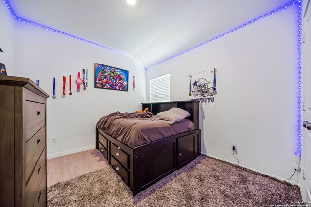 bedroom with light hardwood / wood-style flooring and lofted ceiling