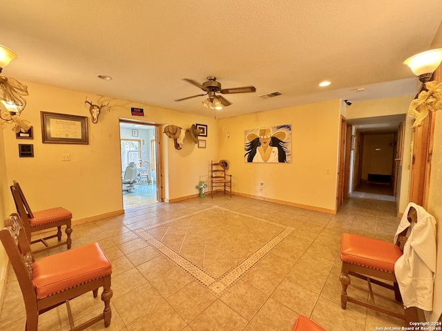 living area featuring light tile patterned floors, a textured ceiling, and ceiling fan