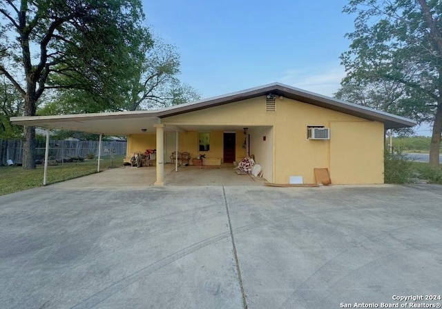 rear view of property featuring a carport and an AC wall unit